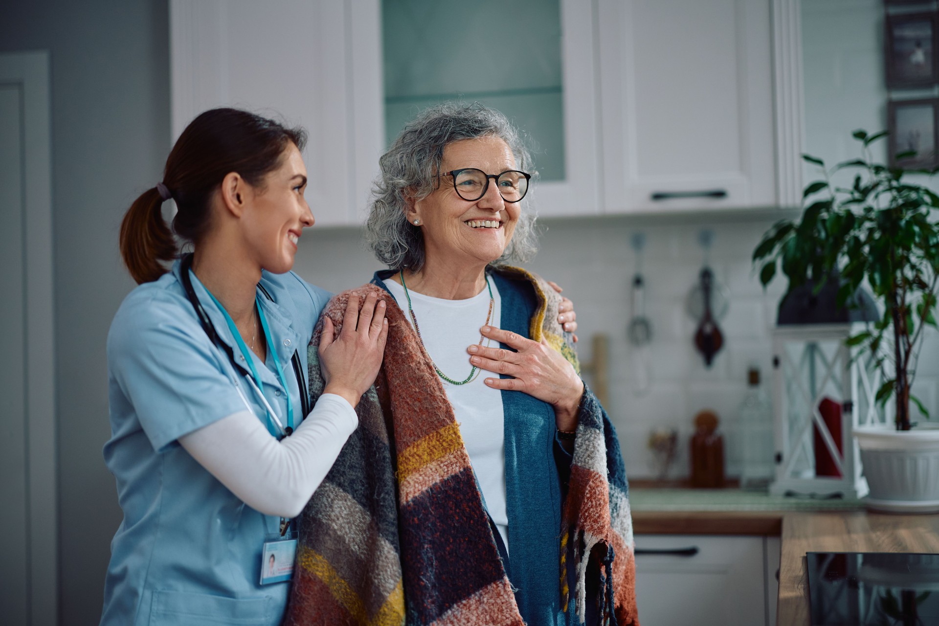 Caring nurse embracing senior woman during a home visit.